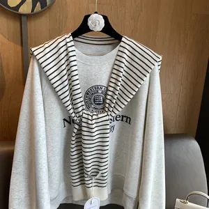 Detail showing classic striped knit shawl draped over a vintage gray collegiate sweatshirt