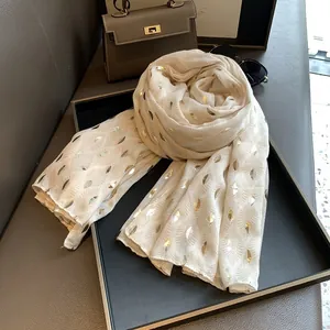 Detail van crème katoenen linnen sjaal met goudkleurige bladprint en lichte textuur