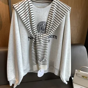 Detail of light grey sweatshirt with black and white striped knit shawl over shoulders