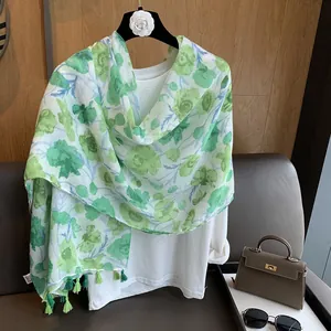 Détail d'une écharpe fleurie verte avec des franges élégantes et une texture légère