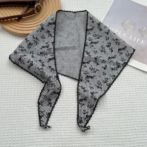 Dettaglio di foulard a righe floreali con pizzo nero per collo o decoro borsa