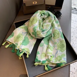 Détail d'une écharpe à fleurs avec feuilles vertes et glands décoratifs multicolores