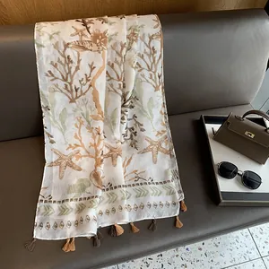 Detail of coral and starfish print scarf with fringe trim on a luxury leather surface