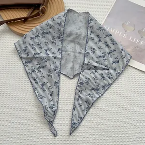 Dettaglio del foulard a triangolo a righe blu e bianche con fiori e bordi a onde