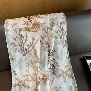 Detail of coral and starfish print on lightweight fabric draped on a leather sofa