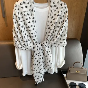 Detail of white cotton scarf featuring black heart patterns and matching fringe edges