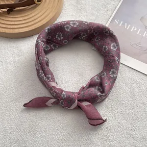 Detail of burgundy floral silk neckerchief tied in a loop on a lifestyle background