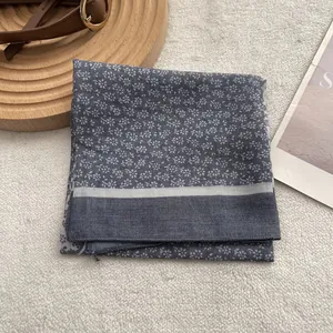 Detail of blue floral cotton scarf neatly folded on white plush surface with vintage props