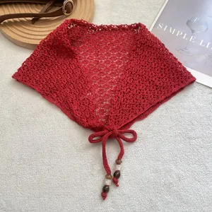 Écharpe triangle rouge en maille ajourée avec perles sur un tapis texturé