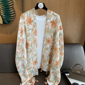Détail d'un châle à imprimé fleuri avec des franges sur tissu mousseline léger