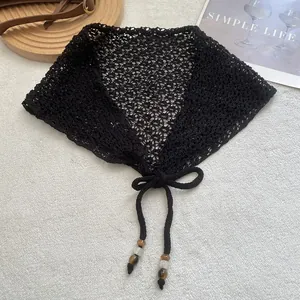 Foulard triangle noir au crochet avec perles sur un fond en tissu blanc et des accessoires