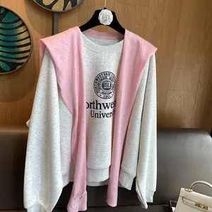 Detail of light gray varsity sweatshirt paired with a pink hollow-out knit shawl wrap