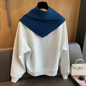 Détail du châle en tricot à losanges bleu marine sur un pull en laine crème chic
