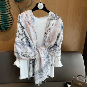 Detail of coral and starfish print scarf with delicate grey tassel trim on white fabric