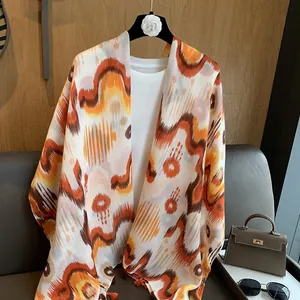 Artistic desert headscarf with orange wave patterns and tassels for beach sun protection
