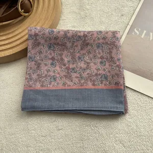 Detail of pink floral silk scarf with blue border on a wooden tray with a leather belt