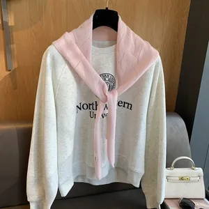 Détail d'un châle en laine rose à losanges superposé sur un sweat-shirt universitaire gris