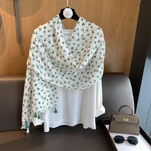 Detail of white cotton linen scarf with green heart print and delicate tassel edges