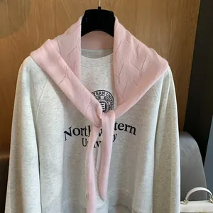 Châle en tricot rose à texture ajourée noué sur un sweat-shirt universitaire gris clair