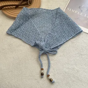 Détail d'un châle au crochet bleu clair avec des perles décoratives sur les liens
