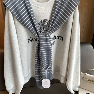 Detail of blue striped knit shawl layered over a grey Northwestern University sweatshirt