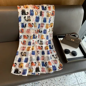 Detailed view of white cotton linen scarf with colorful cartoon cat print on a leather sofa