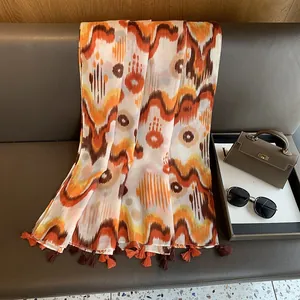 Close-up of exotic patterned linen shawl with orange fringes on leather bench