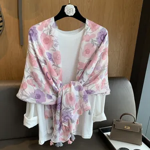 Détail d'une écharpe à fleurs avec de délicats pompons roses et violets sur chemise