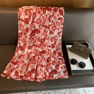 Dettaglio del motivo a foglie rosse con bordi dorati su una sciarpa in seta leggera