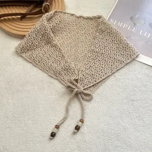 Gros plan d'une écharpe de hanche beige au crochet avec motifs ajourés et liens perlés