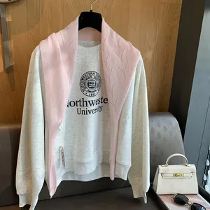 Détail d'un sweat en laine grise avec logo et châle en tricot rose superposé dessus