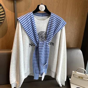 Detailed close-up of a striped knit shawl draped over a grey university print sweatshirt