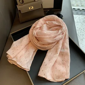 Close-up of pink cotton linen scarf with gold foil details on a leather tray