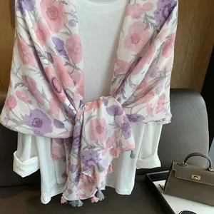 Détail du châle en mousseline florale avec pompons roses et imprimés de fleurs mauves