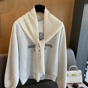 Détail d'un sweat-shirt gris avec un châle en maille ajourée blanche et nœud élégant
