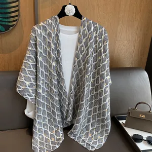 Detail van een lichtgewicht linnen sjaal met goud en zwart bladprint op wit basis