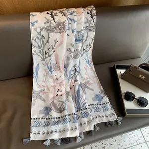 Close-up of cotton linen scarf featuring blue coral prints and grey tassel details