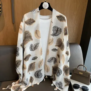 Detail of white cotton linen scarf with leopard leaf print and white fringe accents