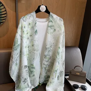 Detail view of lightweight white scarf with tropical green palm leaf print over a t-shirt