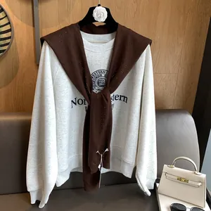 Detail of light grey sweatshirt styled with a dark brown hollow knit shawl accessory