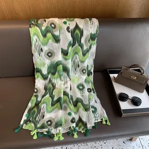 Detail of green and white tie-dye cotton linen scarf with elegant tassels on a bench