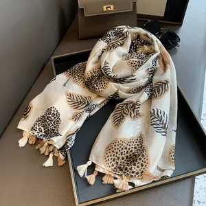 Detail of leopard print scarf with leaf pattern and tassels on leather tray