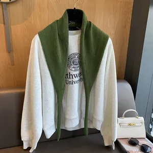 Détail d'un châle en laine tricotée vert foncé sur un sweat-shirt gris clair