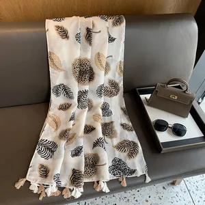 Detail of the animal print scarf with leaf patterns and beige tassel edge decoration