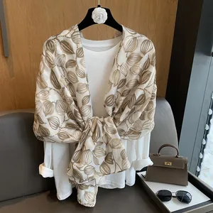 Dettaglio di sciarpa di seta beige vintage con stampa a foglia oro e nodo decorativo