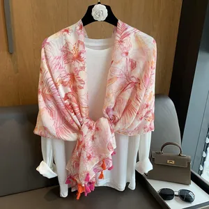 Detail of floral chiffon scarf with dual-tone pink and orange tassels on a hanger