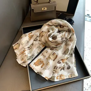 Close-up of cotton linen scarf featuring colorful cartoon cat prints on beige fabric