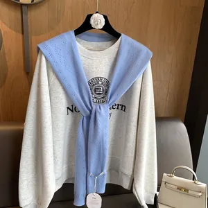 Detail of light blue hollow knit shawl paired with a vintage university sweatshirt