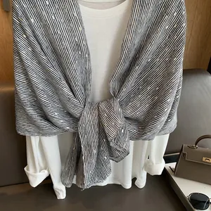 Detail of light cotton linen scarf with black and white stripes and gold foil accents
