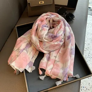 Vue détaillée d'un châle à imprimé floral avec des glands roses et gris sur le bord